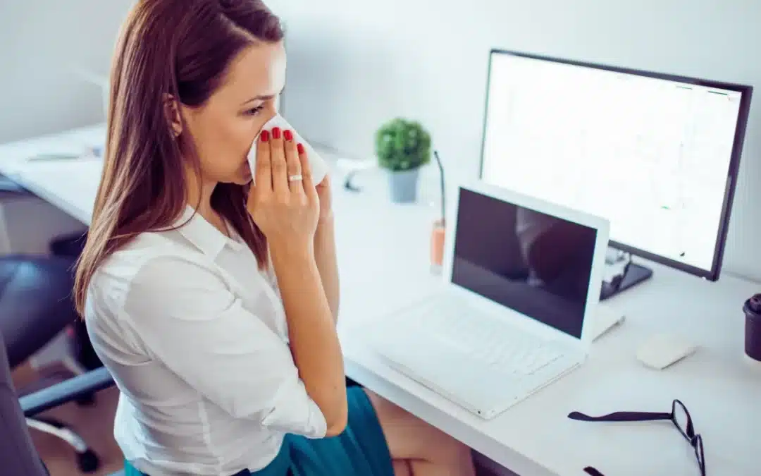 Employee blowing nose in office during flu season
